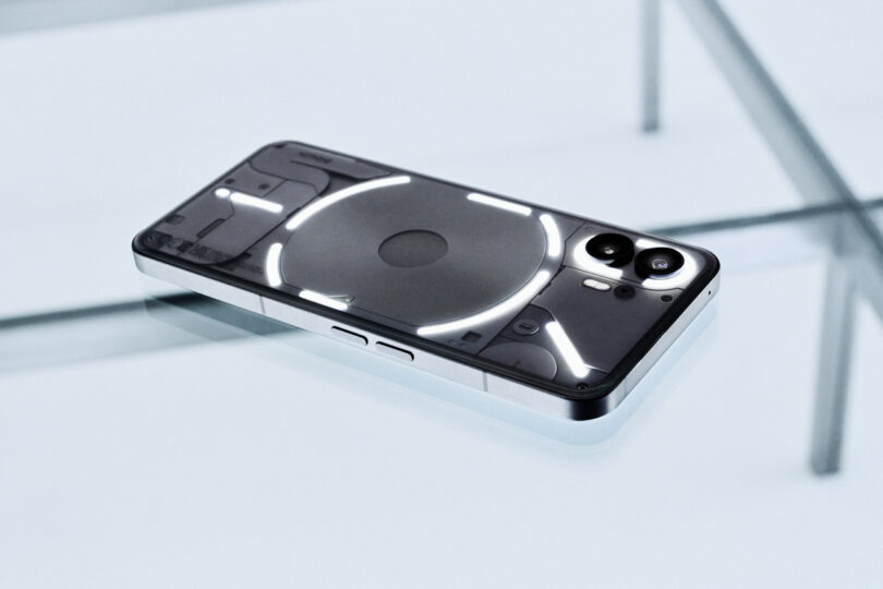 A smartphone with a transparent back cover and illuminated white LED design showcases cutting-edge technology as it rests on a glass surface.