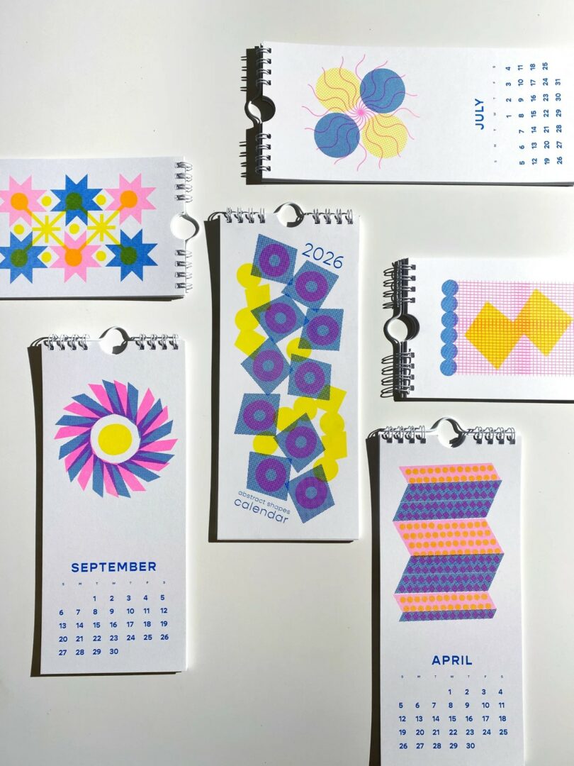 A collection of 2026 desk calendar pages with geometric, colorful patterns for various months, arranged on a white surface—a vibrant showcase of 2026 calendars.