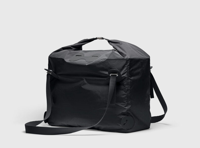 A square-shaped black nylon PARSEL EVA Tote System bag with a top handle, adjustable shoulder strap, and minimalist design against a plain light background.