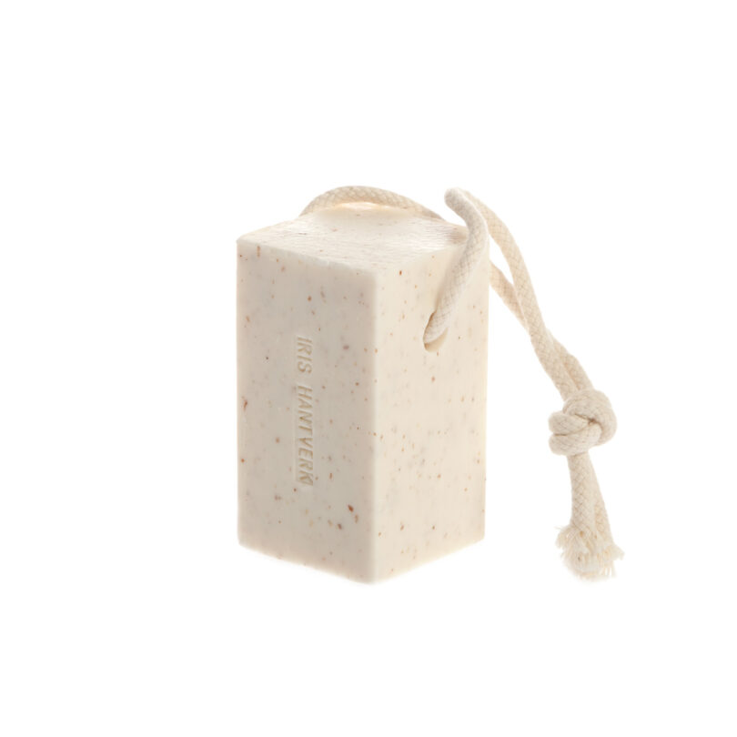 A rectangular bar of soap with embedded flecks and a looped rope attached, photographed on a white background—an ideal pick for any 2025 Gift Guide.