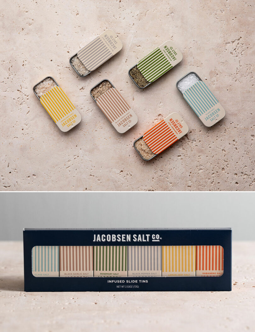 Five small tins of Jacobsen Salt Co. infused salts with striped lids are shown above their original packaging, which displays all five tins in a row.