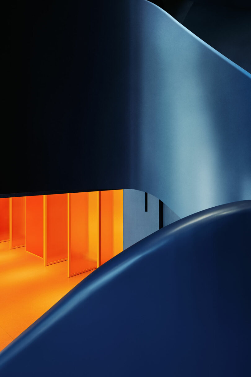 Abstract architectural interior with curved dark blue walls and a bright orange-lit area featuring transparent panels.