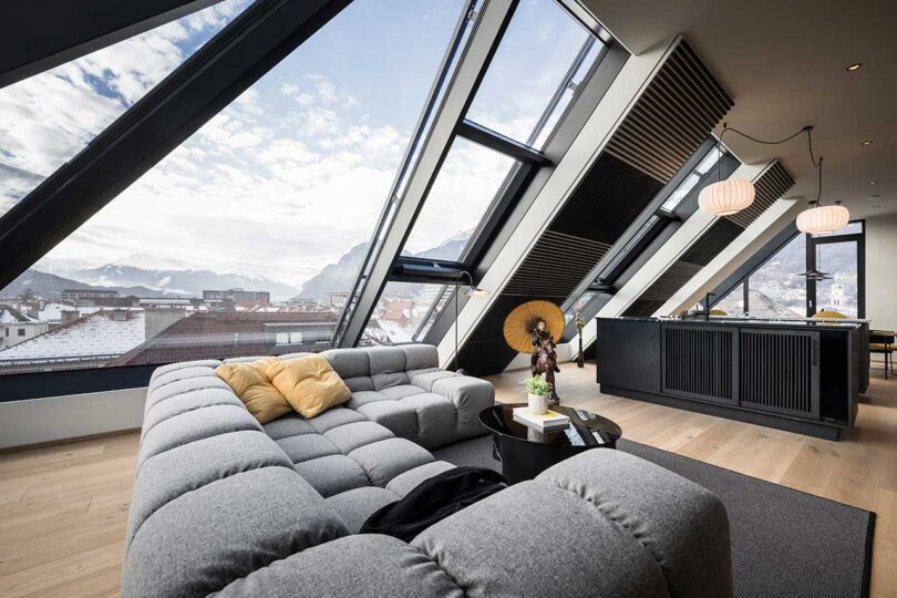 modern apartment interior with slanted glass walls and large grey section