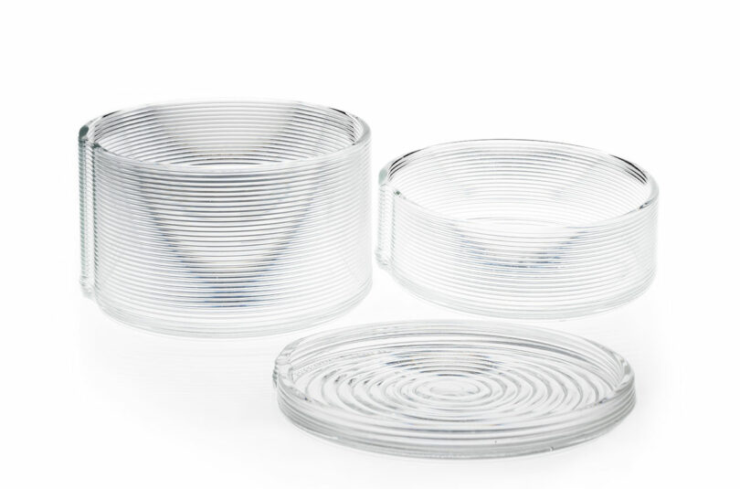 Three clear, round glass dishes of varying heights with horizontal ridged patterns are arranged side by side on a white background.