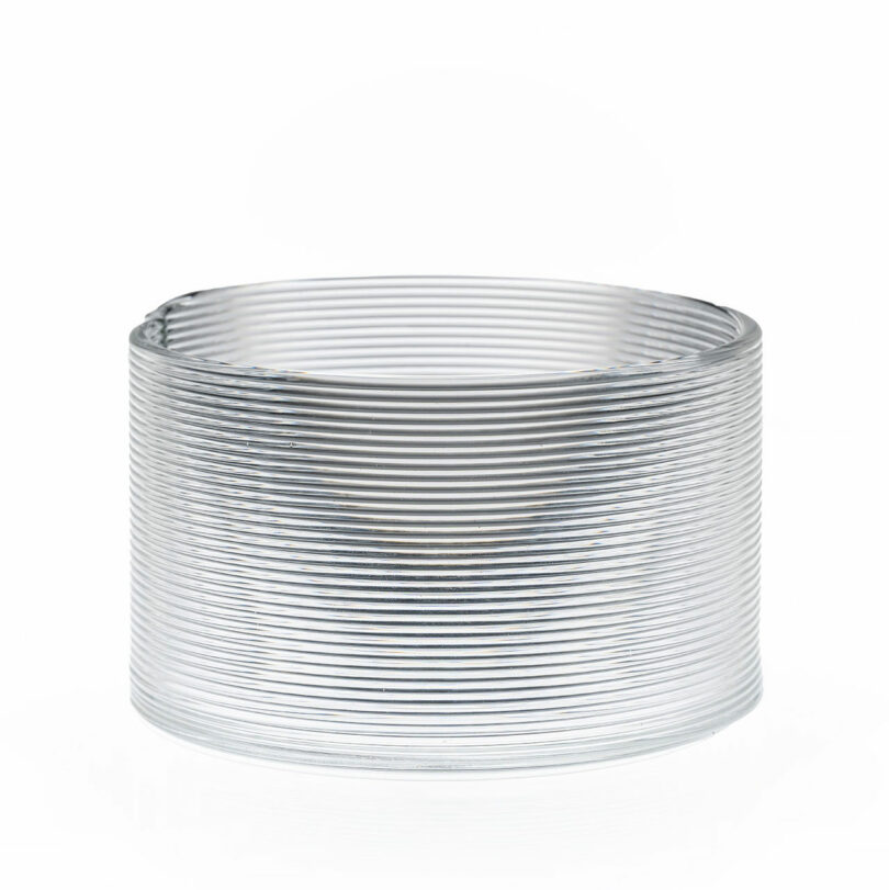 A coiled, transparent plastic slinky toy is standing upright on a white background.